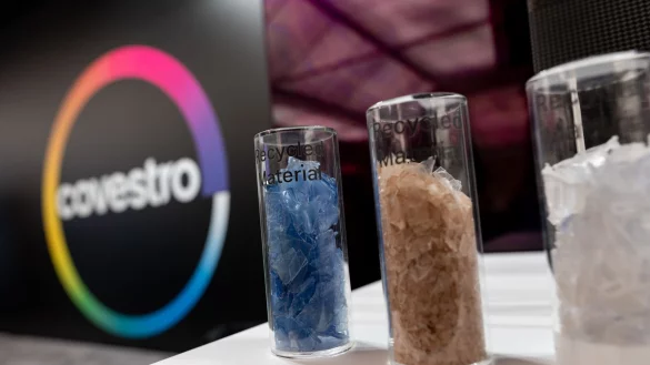 Eine deutsche Firma wird arabisch: Das Logo des Spezialchemie-Konzerns in einem Firmen-Showroom, davor Gläser mit Covestro-Materialien. - © Fabian Strauch/dpa