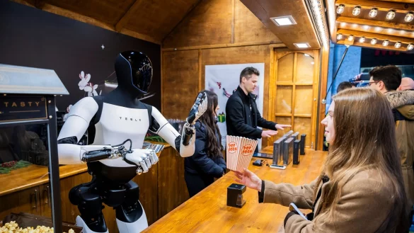 Der humanoide Roboter &laquo;Optimus&raquo; von Tesla verteilt bei seiner Vorstellung in der Mall of Berlin Popcorn an eine Besucherin. - &copy; Christoph Soeder/dpa