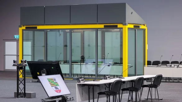 Ein Blick in den Gerichtssaal auf den Platz für die Zeugen und die Glaskabine, in der der Angeklagte während der Verhandlungen sitzt. (Archivbild) - © Jan Woitas/dpa