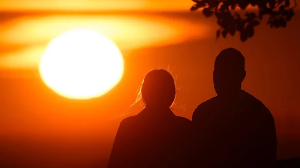 Ein Paar bei Sonnenaufgang - © Julian Stratenschulte/dpa