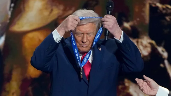 US-Präsident Trump hängt sich die FIFA-Medaille selber um. - © Chris Carlson/AP/dpa