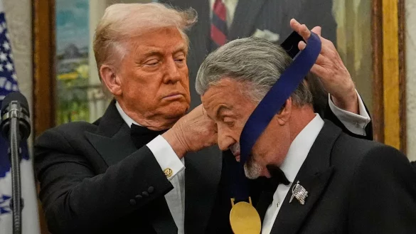 US-Präsident Donald Trump hängt der Actionfilm-Ikone Sylvester Stallone eine Medaille um. - © Julia Demaree Nikhinson/AP/dpa