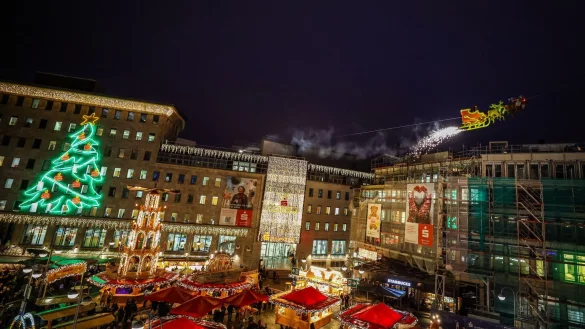 In einem Schlitten, der an einem Stahlseil befestigt ist, fliegt der Weihnachtsmann zwei Mal täglich über den Weihnachtsmarkt in Bochum. - © Christoph Reichwein/dpa
