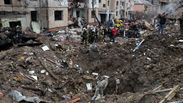 Rettungskr&auml;fte stehen neben einem Krater in der N&auml;he besch&auml;digter Wohngeb&auml;ude nach einem russischen Raketenangriff. - &copy; -/Ukrinform/dpa