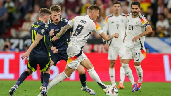 Deutschlands Toni Kroos (M) setzt sich gegen Schottlands Ryan Christie und Scott McTominay durch. - © Christian Charisius/dpa