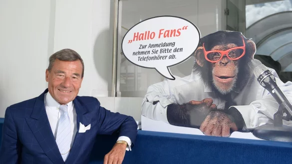 Wolfgang Grupp senior mit einem Werbeschild, auf dem der bekannte Werbe-Affe "Charly" abgebildet ist. - &copy; picture alliance / Patrick Seeger/dpa