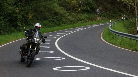 Ein Motorradfahrer f&auml;hrt bei Vossenack durch eine Serpentine mit aufgemalten Kreisen auf der Fahrbahn. - &copy; Oliver Berg/dpa