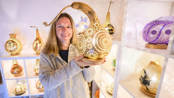 Virginia Lauterbach pr&auml;sentiert eine ihrer handgefertigten K&uuml;rbislampen in der Kalebassenmanufaktur in B&uuml;ckeburg. - &copy; Julian Stratenschulte/dpa