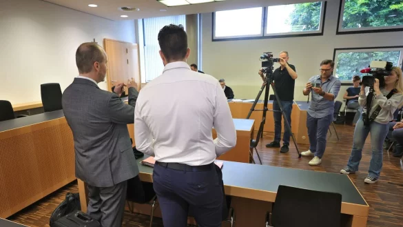 Der Angeklagte (Mitte) steht mit seinem Anwalt im Verhandlungssaal. - © Karl-Josef Hildenbrand/dpa