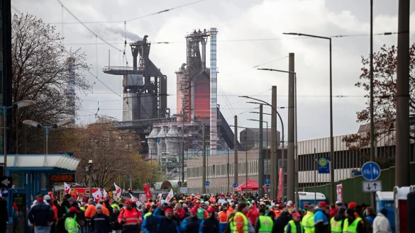 Teilnehmer einer Kundgebung laufen vor den Hochh&ouml;fen des Werks von Thyssenkrupp. - &copy; Fabian Strauch/dpa