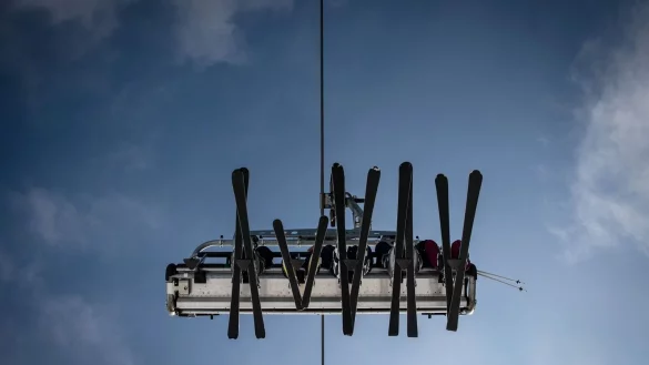 Skier in einem Lift zeichnen sich vor dem blauen Himmel ab. - &copy; Bernd Thissen/dpa/Symbolbild