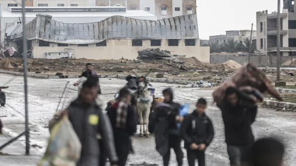 Ein israelischer Panzer ist zu sehen, w&auml;hrend Pal&auml;stinenser das Nasser-Krankenhaus und die angrenzenden Schulen verlassen. - &copy; Mohammed Talatene/dpa