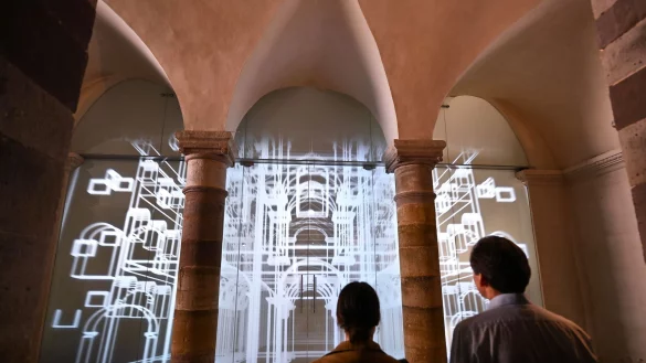 Vertreter des Presseteams stehen nach der Pressekonferenz vor der Medienwand im Unesco-Welterbe Corvey auf der eine 3D-Animation des Westwerks zu sehen ist. - &copy; Bernd Thissen/dpa