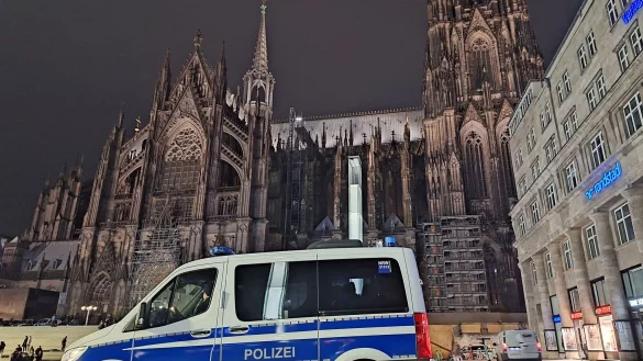 Ein Einsatzfahrzeug der Polizei steht vor dem Dom. - © Sascha Thelen/dpa/Archivbild