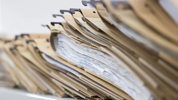 Zahlreiche Akten sind auf einem Schreibtisch ausgelegt. Bei den Staatsanwaltschaften in NRW t&uuml;rmt sich ein Berg von unerledigten Ermittlungsverfahren. - &copy; Lando Hass/dpa