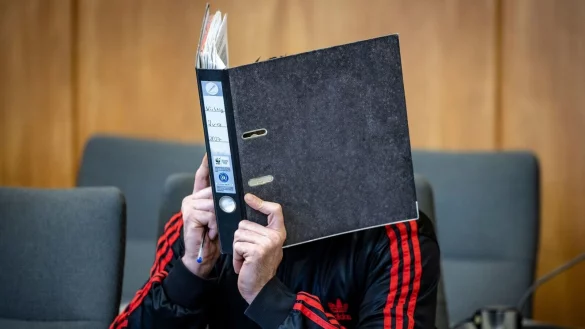 Der Angeklagte verbirgt im Essener Landgericht sein Gesicht hinter einem Aktenordner. - © Christoph Reichwein/dpa