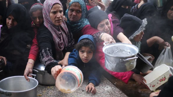 Pal&auml;stinenser stehen w&auml;hrend der israelischen Luft- und Bodenoffensive f&uuml;r die kostenlose Verteilung von Lebensmitteln an. - &copy; Hatem Ali/AP/dpa