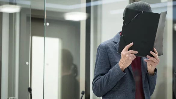 Der Angeklagte h&auml;lt sich zu Beginn des Prozesses eine Mappe vors Gesicht. Der 80-J&auml;hrige will sich zu den Vorw&uuml;rfen nicht &auml;u&szlig;ern. - &copy; Sebastian Christoph Gollnow/dpa