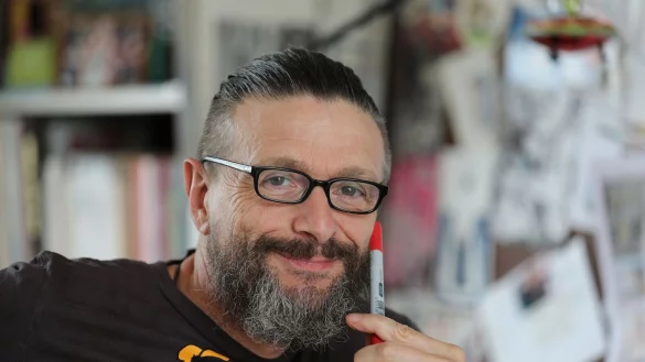 Ralf K&ouml;nig, Comic-Zeichner und Autor, sitzt in seinem Atelier und l&auml;chelt. - &copy; Oliver Berg/dpa