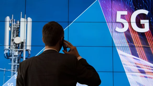 Ein Mann steht bei der Auktion von Frequenznutzungsrechten im Geb&auml;ude der Bundesnetzagentur vor einer Leinwand mit der Aufschrift "5G". - &copy; Boris Roessler/dpa