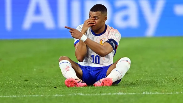 Diagnose Nasenbeinbruch: Frankreichs Kylian Mbapp&eacute; sitzt beim Spiel gegen &Ouml;sterreich auf dem Rasen und h&auml;lt seine verletzte Nase. - &copy; Marius Becker/dpa