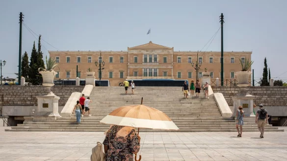 Eine Frau sch&uuml;tzt sich mit einem Sonnenschirm auf dem Syntagma-Platz in Athen vor der Sonne: Warme Luftmassen sorgen f&uuml;r Temperaturen von &ouml;rtlich bis zu 45 Grad. - &copy; Socrates Baltagiannis/dpa