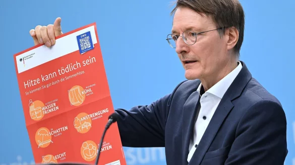 Bundesgesundheitsminister Karl Lauterbach (SPD) h&auml;lt ein Plakat zum Thema Hitzeschutz hoch. - &copy; Britta Pedersen/dpa