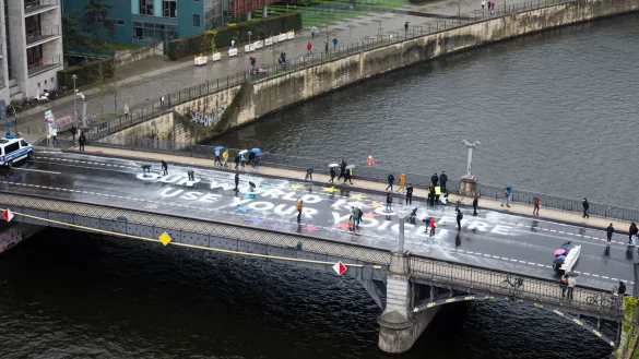 Klimaaktivisten der Bewegung Fridays for Future malen auf der Marschallbr&uuml;cke in Berlin den Schriftzug &laquo;Our world is on fire - use your voice!&raquo;. - &copy; Christophe Gateau/dpa