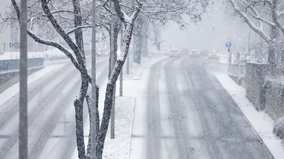 Nur langsam kommen Autos in der Innenstadt im dichten Schneetreiben voran. - © Rolf Vennenbernd/dpa