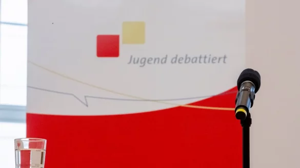 Ein Mikrofon und ein Glas Wasser stehen vor der Veranstaltung &laquo;Jugend debattiert mit Spitzenkandidaten&raquo; auf einem Rednerpult. - &copy; Christoph Soeder/dpa/Archivbild