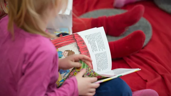 Ein M&auml;dchen liest in einer Kita in Hamburg in einem Buch. - &copy; Daniel Reinhardt/dpa