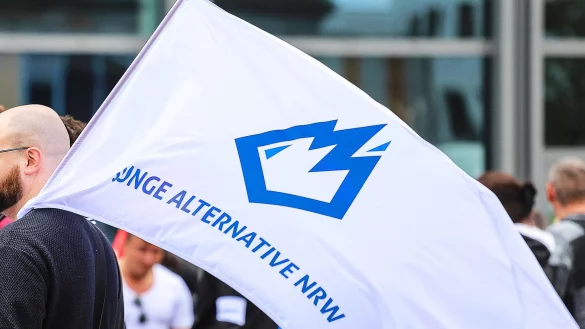 Ein Mitglied der &laquo;Jungen Alternative&raquo; (JA) tr&auml;gt auf einer Wahlkampfveranstaltung eine Fahne mit dem Logo der Organisation. - &copy; Alex Talash/dpa