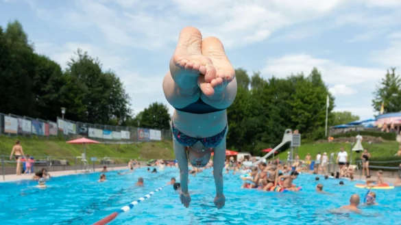 Ein Badegast springt von einem Startblock in das Wasserbecken von einem Freibad. - &copy; Friso Gentsch/dpa/Symbolbild