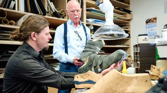 Schuhmacher Georg Wessels (r) bespricht in seiner Werkstatt mit seinem Neffen und Orthop&auml;die-Schumachermeister Adrian Wessels die noch unfertigen neuen Schuhen f&uuml;r Jeison Rodriguez. - &copy; Bernd Thissen/dpa/Produktion