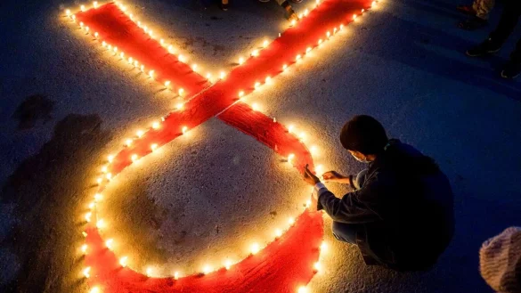 Eine Frau stellt Kerzen auf, die eine rote Schleife formen - ein weltweit anerkanntes Symbol f&uuml;r die Solidarit&auml;t mit HIV-Infizierten. - &copy; Sunil Pradhan/SOPA Images via ZUMA Wire/dpa