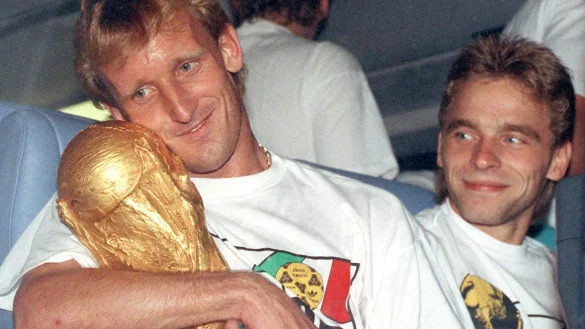 Andreas Brehme (l) mit dem WM-Pokal nach dem Finalsieg 1990 gegen Argentinien. Rechts daneben sein Mitspieler Thomas H&auml;&szlig;ler. - &copy; Frank Kleefeldt/dpa