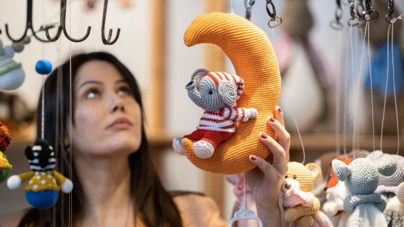 Model Claudia betrachtet zum Start der Handarbeitsmesse Creativa 2023 eine geh&auml;kelte Baby-Spieluhr. - &copy; Bernd Thissen/dpa