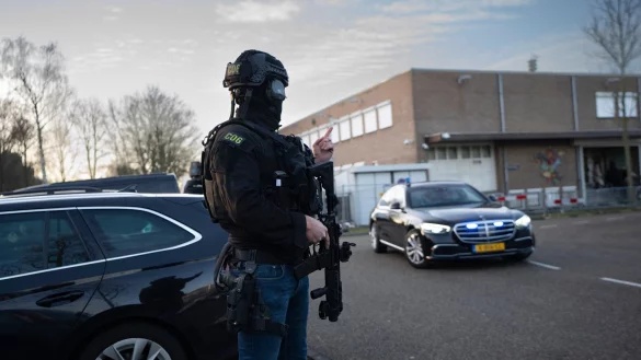 Maskierte und bewaffnete niederl&auml;ndische Polizisten bewachen einen Transport mit einigen der Verd&auml;chtigen, die vor dem Hochsicherheitsgeb&auml;ude des Gerichts in Amsterdam eintreffen. - &copy; Peter Dejong/AP/dpa