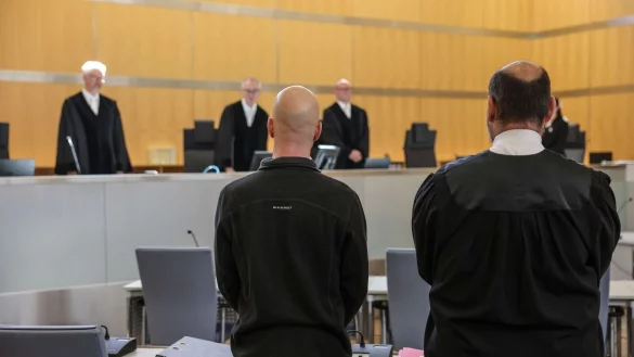 Der Angeklagte (l, vorne) steht neben seinem Anwalt Marvin Schroth (r) im Gerichtssaal. - &copy; Oliver Berg/dpa