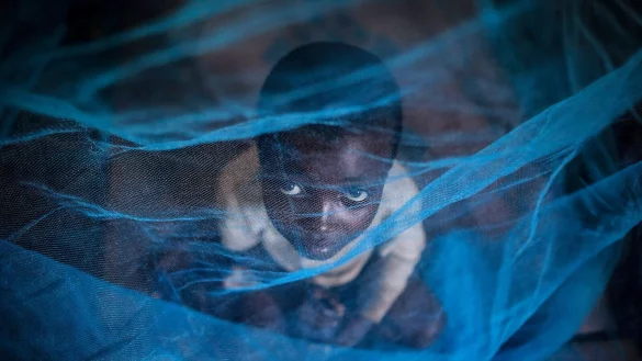 Ein Fl&uuml;chtlingskind aus Burundi sitzt in Gashora, Ruanda, unter einem Moskitonetz: Der Malaria-Erreger wird durch Anopheles-Stechm&uuml;cken &uuml;bertragen. - &copy; Dai Kurokawa/EPA/dpa