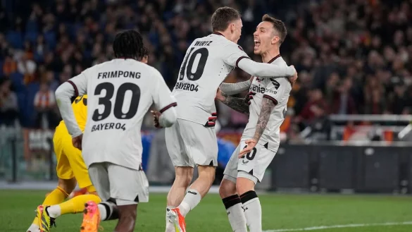 Leverkusens Florian Wirtz (M) bejubelt sein Tor zum 0:1 mit Jeremie Frimpong (l) Alejandro Grimaldo (r). - &copy; Andrew Medichini/AP/dpa