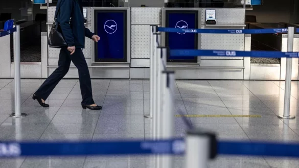 Eine Frau l&auml;uft an Lufthansa-Schaltern zum Check-In am Flughafen D&uuml;sseldorf vorbei. - &copy; Christoph Reichwein/dpa/Archivbild