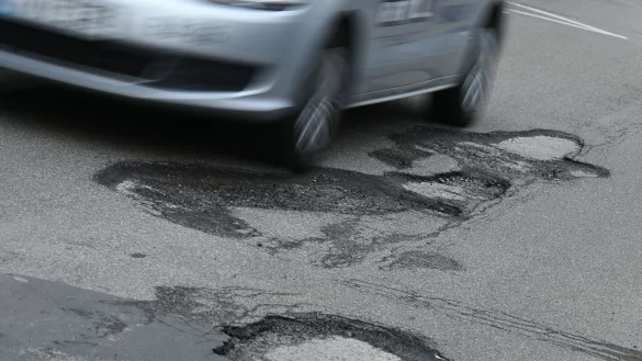 Ein Auto f&auml;hrt im Januar 2023 stadteinw&auml;rts auf der M&ouml;rfelder Landstra&szlig;e im Stadtteil Sachsenhausen durch ein Schlagloch. - &copy; Arne Dedert/dpa/Archivbild