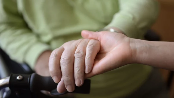 Eine junge Frau h&auml;lt in einem Seniorenpflegeheim die H&auml;nde eines alten Mannes. - &copy; Jens Kalaene/dpa-Zentralbild/dpa/Symbolbild