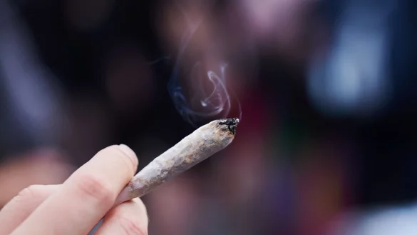 Eine Frau hält einen Joint in der Hand: Cannabis wird von der Liste der verbotenen Substanzen gestrichen. - © Annette Riedl/dpa