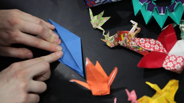 Zwei H&auml;nde falten in Origami-Technik einen Kranich aus Papier. - &copy; Jan Woitas/dpa-Zentralbild/dpa