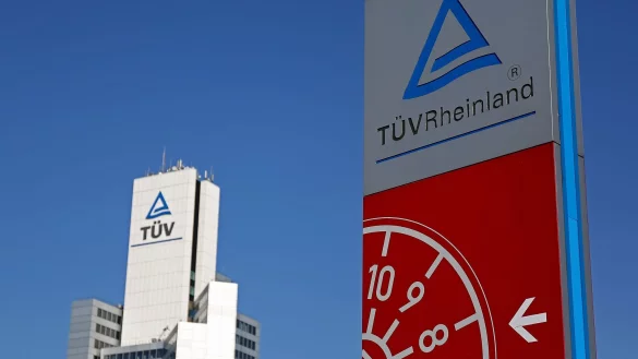 Ein Hinweisschild einer Kfz-Prüfstelle des TÜV Rheinland steht neben der Unternehmenszentrale. - © Oliver Berg/dpa