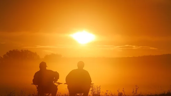 Zwei Angler sitzen auf Campingst&uuml;hlen und schauen sich den Sonnenaufgang in Baden-W&uuml;rttemberg an. - &copy; Thomas Warnack/dpa
