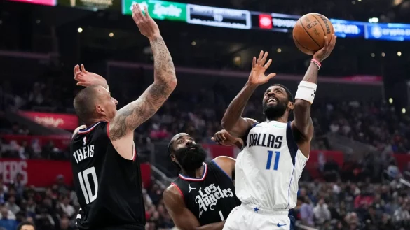 Kyrie Irving (r) von den Dallas Mavericks wirft unter dem Druck von James Harden (M) und Daniel Theis von den Los Angeles Clippers. - &copy; Jae C. Hong/AP/dpa