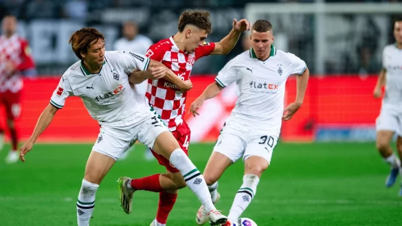 Nach einem harten Kampf trennen sich Gladbachs Ko Itakura (l) und der Mainzer Brajan Gruda (M)und ihre Teams 1:1. - &copy; Marius Becker/dpa